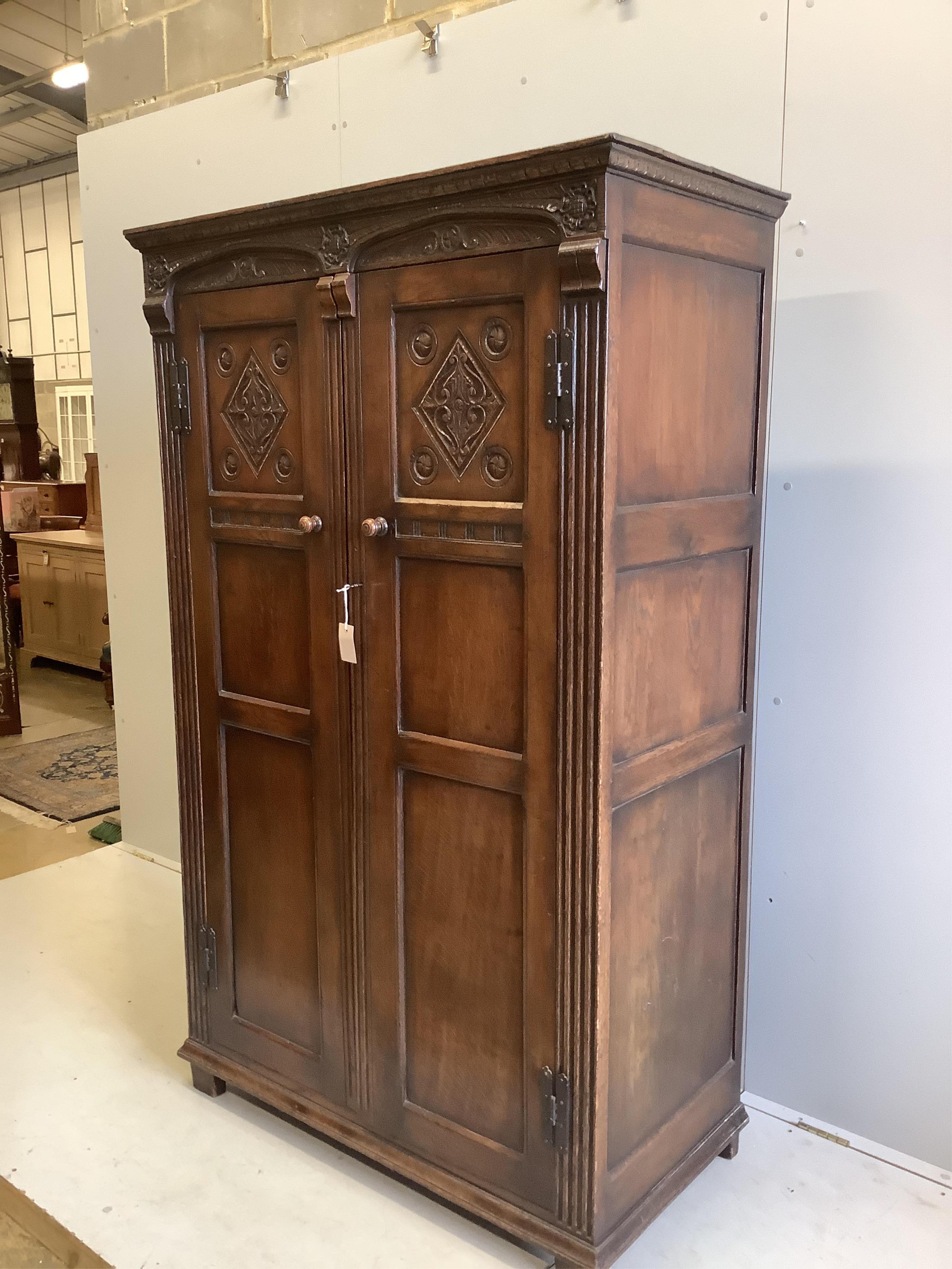 An 18th century style carved oak two door wardrobe, width 112cm, depth 57cm, height 183cm